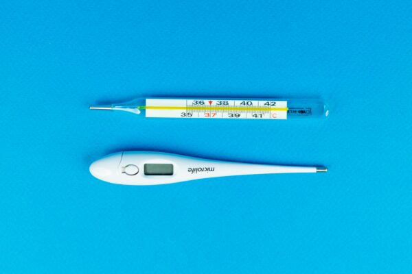 Digital and mercury thermometers on blue background for medical concept.
